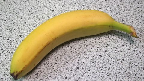 Eine reife, gelbe Banane liegt auf einer grauen Arbeitsplatte und könnte helfen, nach scharfem Essen zu beruhigen.