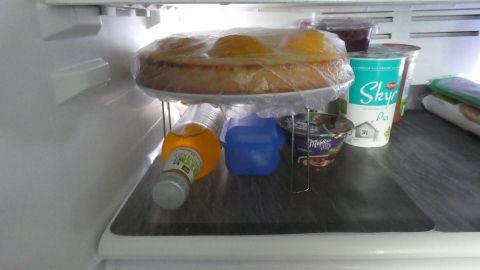 In einem Kühlschrank sind flache Gegenstände wie ein Kuchen und Getränke gestapelt, um Platz zu sparen.