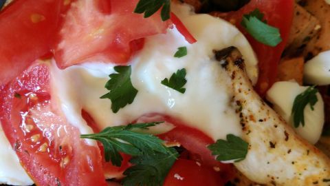 Frischer Tomatensalat mit Kräuterseitlingen, garniert mit Joghurt und Kräutern in einer appetitlichen Anordnung.
