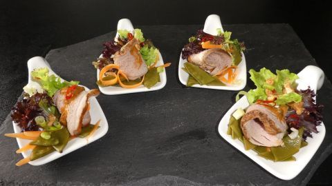 Auf vier weißen Löffeln sind thailändische Filets angerichtet, umgeben von buntem Salat und einer Erdnussdip-Sauce.