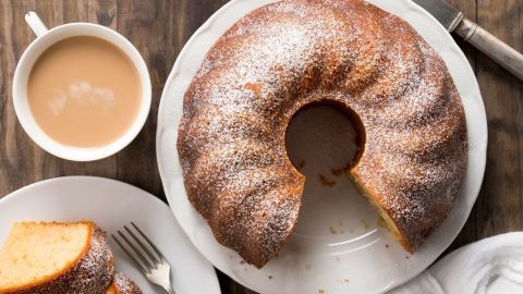 Ein saftiger Kuchen liegt auf einem weißen Teller, umgeben von einer Tasse Kaffee und einem Stück Kuchen.