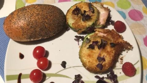 Zucchini-Sandwiches mit Schinken und Käse liegen auf einem Teller, umgeben von Kirschtomaten und einem Glas Rosé.