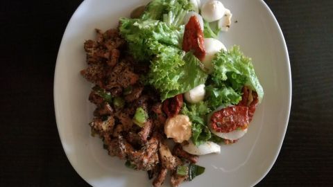 Eine appetitliche Pfifferlings-Selleriepfanne liegt neben einem bunten, frischen Salat auf einem weißen Teller.