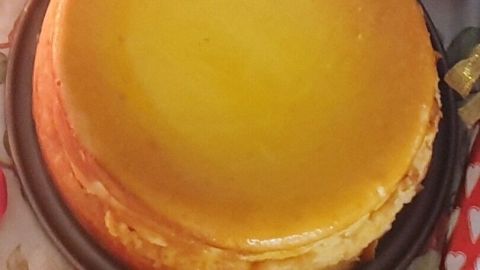 Ein Käsekuchen ohne Boden steht auf einem dekorativen Teller. Der Kuchen hat eine goldbraune Oberfläche und wirkt saftig, umgeben von rustikaler Dekoration.