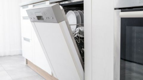 Eine geöffnete Geschirrmaschine steht in einer modernen Küche und ist bereit, Geschirr zu reinigen.