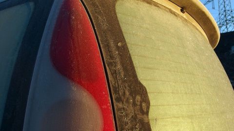 Keine vereisten Autoscheiben mehr am Morgen mit diesem Trick. Ein Auto mit vereisten Scheiben steht in der Morgensonne, während der Frost langsam schmilzt.