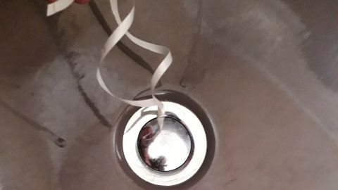 Ein Badewannenstöpsel liegt zentral in der Wanne, mit einem Zugband, um ihn zu betätigen, um Wasser zu halten.