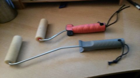 Zwei Malerrollen mit Griffen liegen auf einem Tisch, bereit zum Eincremen von Rücken und Füßen.