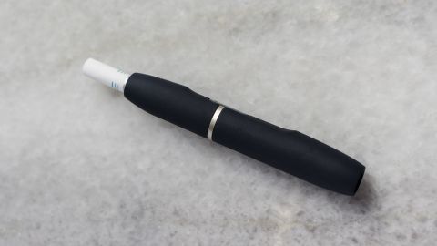 Ein schwarzer IQOS-Stift liegt auf einer grauen Oberfläche und wartet darauf, gereinigt zu werden.