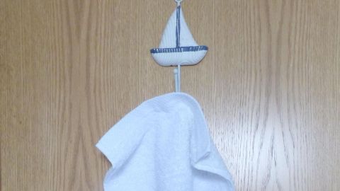 Ein handtuch hängt an einer Tür, umgeben von einer einfachen Holzoberfläche, was einen angenehmen Duft im Badezimmer vermittelt.