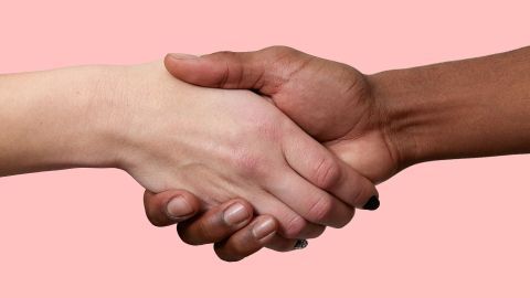 Händedruck symbolisiert Freundlichkeit und Einheit vor einem sanften, rosa Hintergrund, der Harmonie ausstrahlt.
