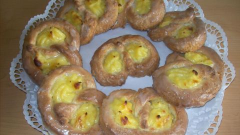 Puddingbrezeln aus leckerem Teig liegen auf einer weißen Servierplatte und laden zum Verzehr ein.