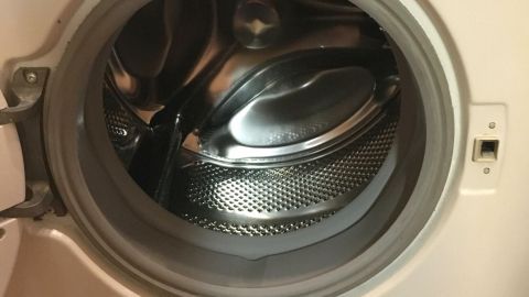 Eine Waschmaschine mit sichtbarem Bullauge steht im Fokus. Sie ist im Einsatz zur Reinigung von Wäsche in einem Haushalt.