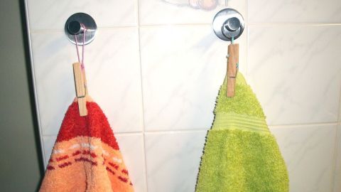 Handtücher hängen an zwei Unterstellern an einer Badezimmerwand, wobei eines rot und das andere grün ist.