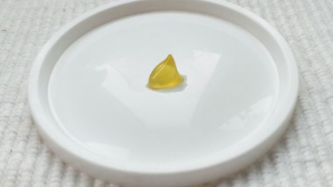 Ein kleiner gelbes Heilölstückchen liegt in einer weißen Schale auf einem weichen, hellen Untergrund.