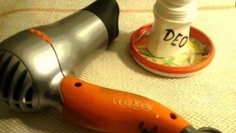Ein Haartrockner liegt neben einem Deo, das in einem kleinen Behälter steht, um Hautreizungen beim Auftragen zu vermeiden.
