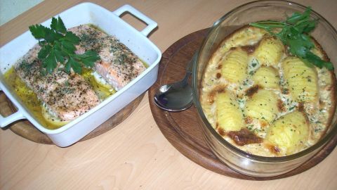 Zitronenlachs liegt in einer Schüssel und Fächerkartoffeln sind daneben auf einem Holzbrett angerichtet.