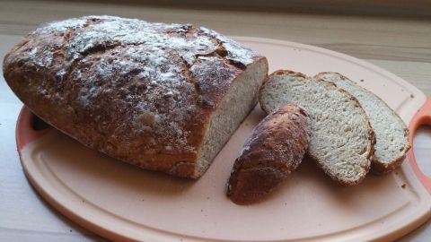Ein frisches, knuspriges Kartoffelbrot liegt auf einem Holzbrett, während einige Scheiben sauber abgeschnitten sind.