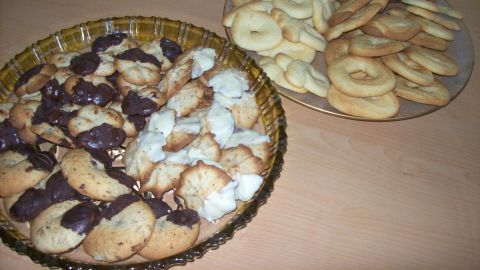 Auf einem Tisch liegen zwei Teller mit klassischem Spritzgebäck, einer mit Schokolade, der andere mit Vanille-Keksen.