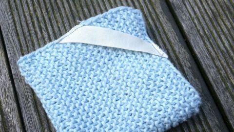 Ein blauer Spüllappen aus Baumwolle liegt auf einer Holzoberfläche, ideal zum Plastikvermeiden und umweltfreundlichem Reinigen.