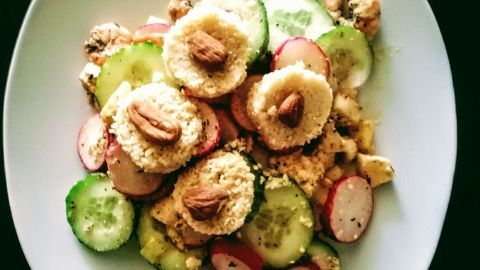 Couscous-Mandeltaler liegen appetitlich auf frischem Gemüse, umgeben von Gurken- und Radieschen-Scheiben.