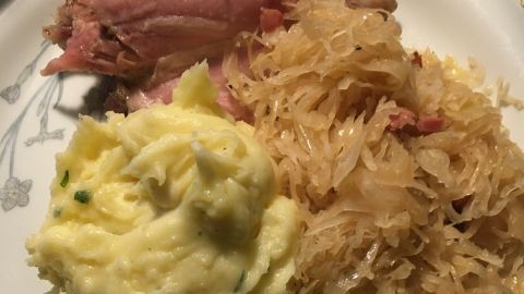 Eisbein liegt auf einem Teller neben Sauerkraut und Kartoffelpüree, serviert in einer gemütlichen Essensatmosphäre.