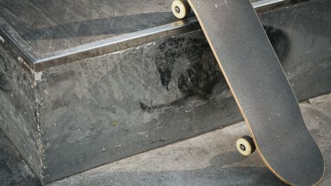 Ein Skateboard liegt auf einer Kante, während ein Rider sich auf die Landung vorbereitet, um Tricks zu zeigen.