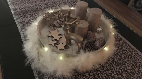 Ein festlicher Tisch ist mit einer schönen Weihnachtsdekoration geschmückt, die Kerzen, Tannenzapfen und glitzernde Lichter umfasst.