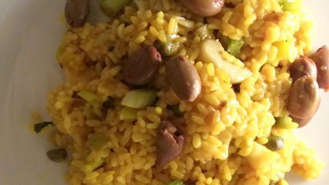 Ein saftiges Safran-Risotto mit buntem Gemüse liegt auf einem weißen Teller, perfekt zum Genießen in einer gemütlichen Küchenumgebung.
