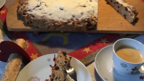 Ein frisch geschnittenes Stück Leipziger Stollen liegt auf einem Teller, während eine Tasse Kaffee daneben steht.