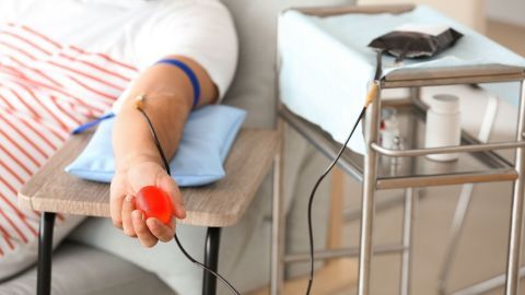 Ein Patient liegt entspannt auf einer Liege, während er Blut spendet. Neben ihm steht ein Gerät zur Blutabnahme.