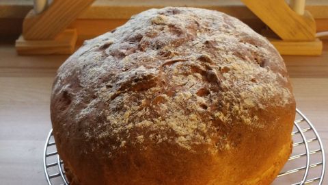 Ein warmes, fluffig saftiges Kartoffelbrot steht auf einem Gitter, umgeben von einem dekorativen Kerzenhalter.