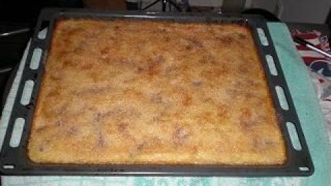 Ein goldbrauner Buttermilch-Kuchen mit Mandarinen liegt auf einem Blech, umgeben von einer grünen Küchenunterlage.