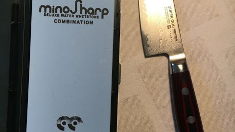 Ein scharfes Messer liegt neben einer Verpackung auf einem Tisch, bereit zum Zwiebeln schneiden ohne Tränen.