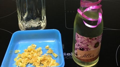 Eine Flasche Wodka steht neben einem kleinen Behälter mit frischem Ingwer, während ein dekorierter Likörflasche im Vordergrund steht.