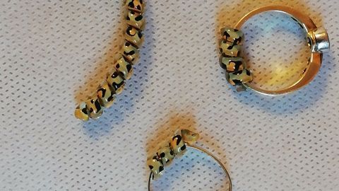 Ein verformter Ring liegt neben zwei weiteren Ringen auf einem hellen, strukturierten Untergrund, die darauf hinweisen, dass er zu weit geworden ist.