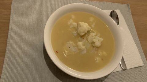 Sämige Kartoffelsuppe in einer weißen Schüssel, serviert auf einem Tisch mit Besteck und einer Serviette.