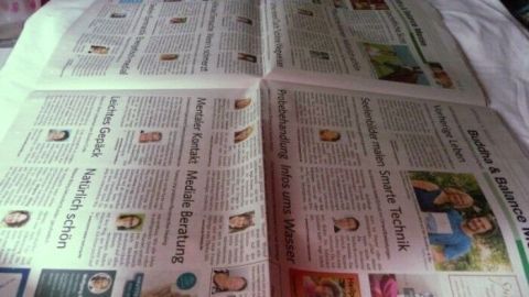 Eine ausgebreitete Zeitungsseite liegt auf einem Tisch, bereit zur Herstellung von Mülltüten aus Zeitungspapier.