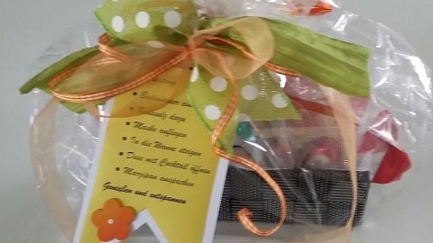 Ein dekoratives Geschenk in Zellophan mit bunten Süßigkeiten und einem grün-weißen Band, passend als Mitbringsel für jeden Anlass.