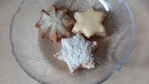 Eine klare Glasschale enthält drei gefrorene Kekse, die in verschiedenen Farben leicht glitzern.