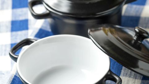 Schwarze Kochtöpfe stehen auf einem karierten Tuch, einer ist geöffnet. Perfekt für das Essen von gestern im Kühlschrank.
