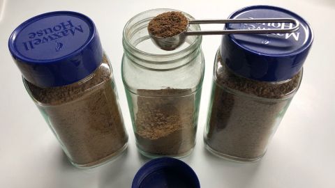Ein Löffel mit koffeinfreier Kaffee-Granulate wird aus einem Glas gehoben, um eine leckere Drink-Zubereitung zu starten.