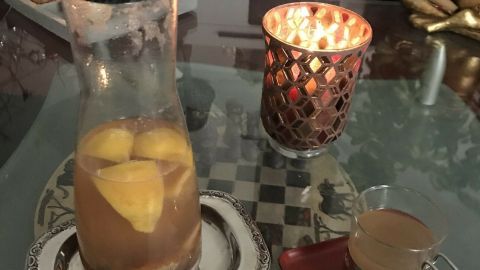 Ein Krug mit Getränk und Ingwerwürfeln steht auf einem Tisch neben einer Tasse, um das Immunsystem zu stärken.