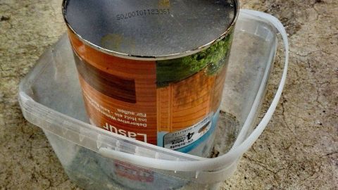 Ein Eimer mit Lack steht in einer Kunststoffschale, ideal zum Aufbewahren und Verlängern der Haltbarkeit von Lacken.