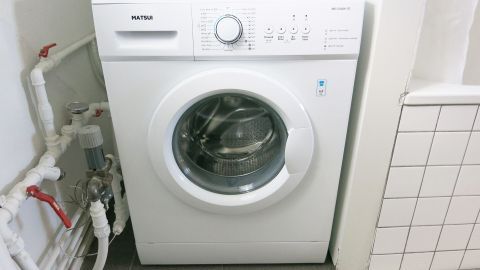 Eine Waschmaschine steht in einem sauberen, hellen Raum, bereit, Wäsche effizient zu reinigen und Waschmittel zu sparen.