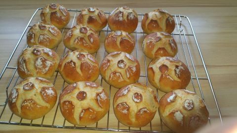 Frisch gebackene Brötchen liegen warm auf einem Kuchengitter, umgeben von einer hellen Holzoberfläche.