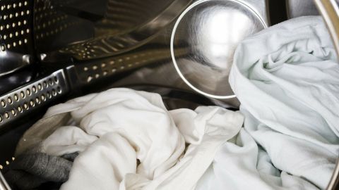 Weißer Wäschehaufen liegt in einer Waschmaschine, um die vergraute Wäsche wieder weiß zu bekommen.