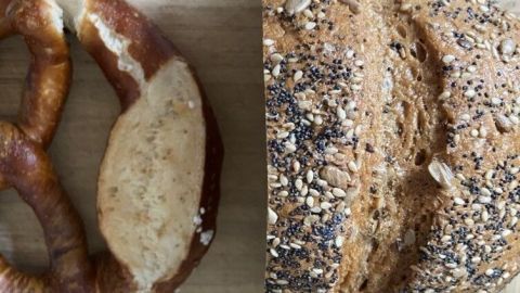 Ein frisches, knackiges Brot und eine weiche Brezel liegen auf einem Holzbrett, um genießbar gemacht zu werden.