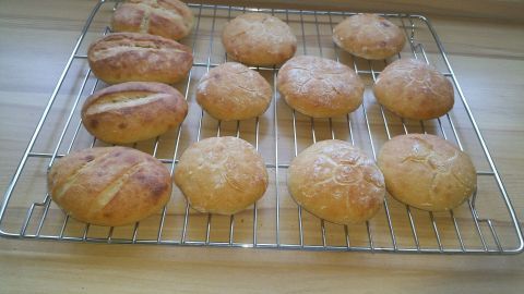 Weizenbrötchen liegen frisch gebacken auf einem Kuchengitter und warten darauf, serviert zu werden.