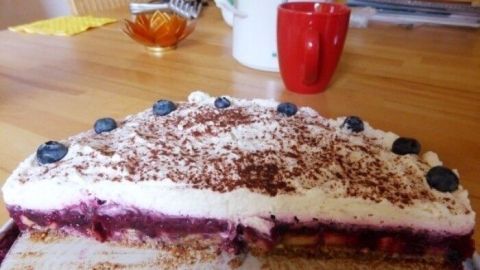 Eine fruchtige Low-Carb-Torte liegt auf einem Tisch und ist mit Schokolade und Beeren garniert, bereit zum Genießen.